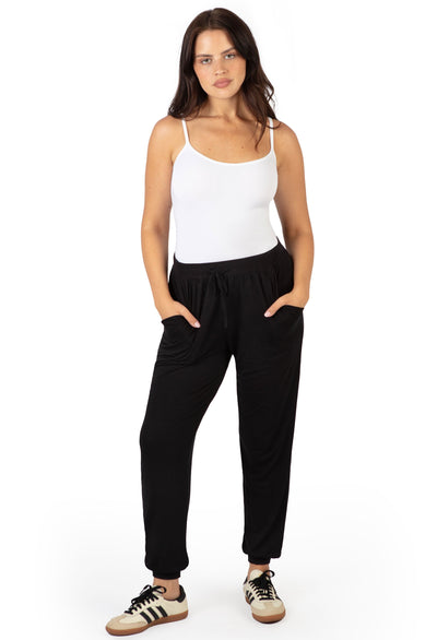 Woman wearing B Free Bamboo Travel Pants & Camisole Set in black pants and white cami, hands in pockets, front view